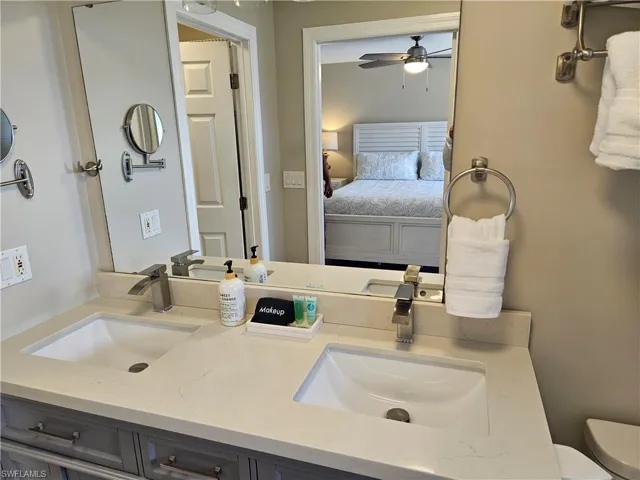 Bathroom with double vanity, toilet, ceiling fan, and a sink