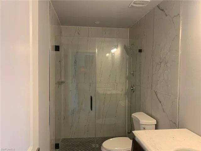 Bathroom with vanity and a marble finish shower