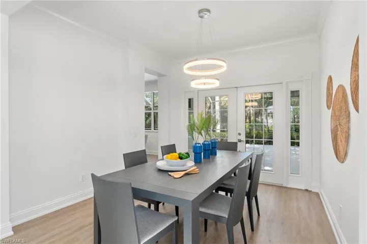 A formal dining space with custom light fixture and french doors provides a perfect space for gathering