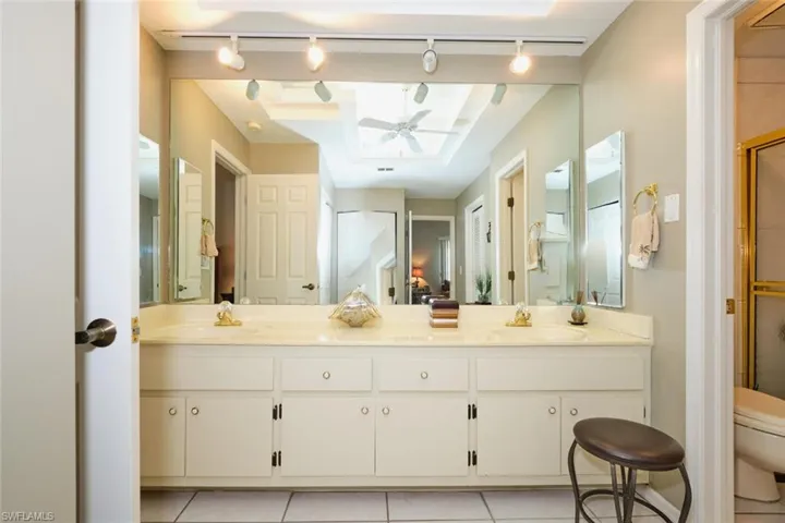 Bathroom featuring tile patterned flooring, toilet, rail lighting, ceiling fan, and vanity