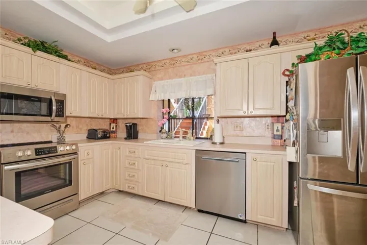 Kitchen featuring appliances with stainless steel finishes, light tile patterned floors, sink, and ceiling fan