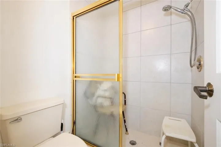 Bathroom featuring toilet and a shower with shower door