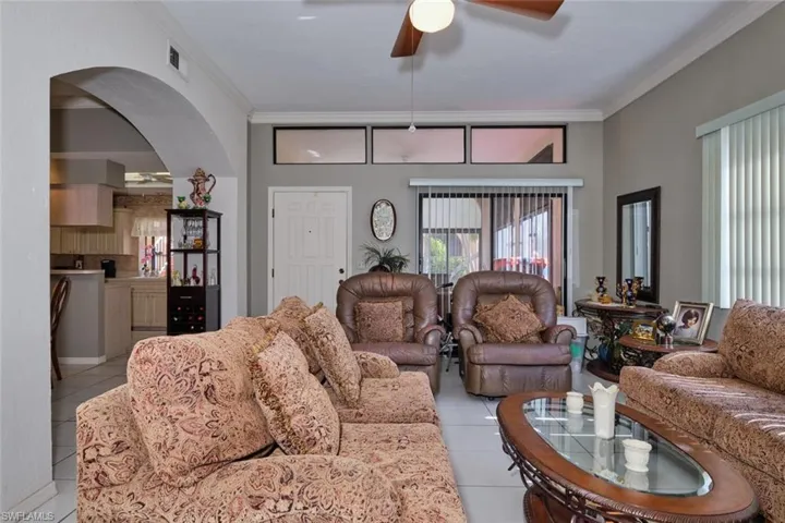 Living room featuring crown molding, ceiling fan, and light tile patterned flooring