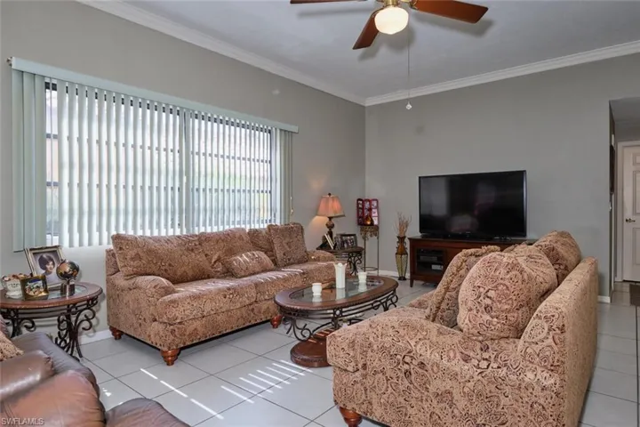 Living room featuring ornamental molding, a wealth of natural light, light tile patterned floors, and ceiling fan
