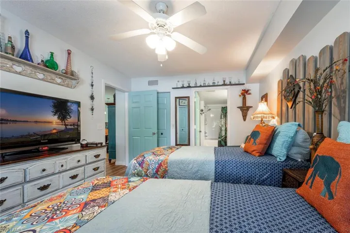 Bedroom with a ceiling fan, visible vents, ensuite bath, and wood finished floors