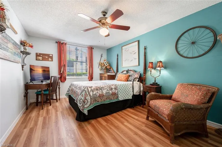 Bedroom featuring a textured ceiling, baseboards, and wood finished floors