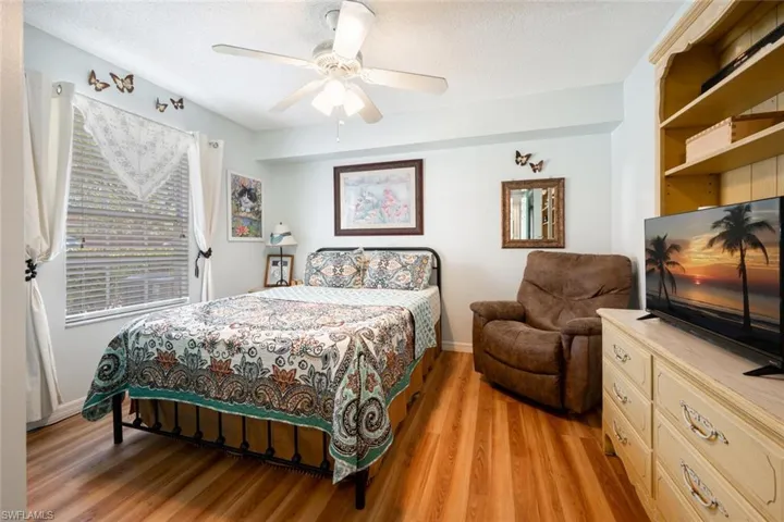 Bedroom with light wood finished floors, a textured ceiling, and a ceiling fan