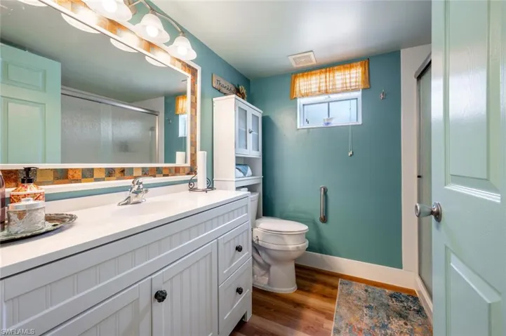 Full bathroom with toilet, wood finished floors, visible vents, vanity, and a shower stall