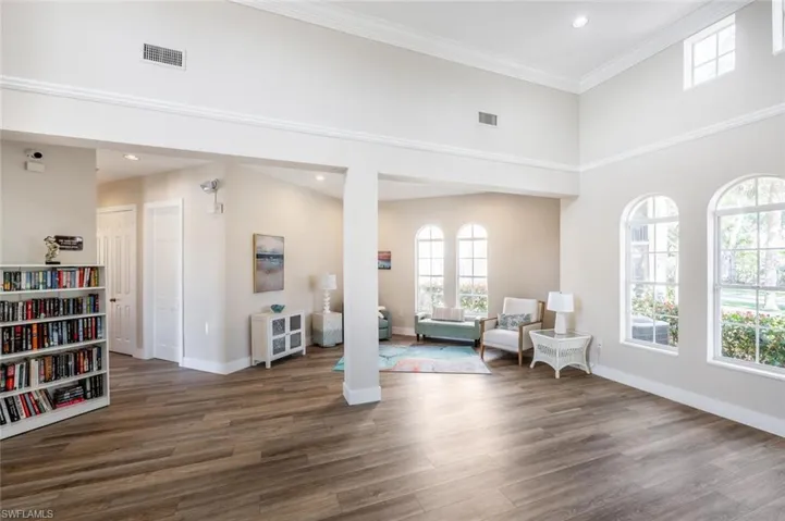 Sitting room with crown molding, visible vents, a high ceiling, wood finished floors, and baseboards