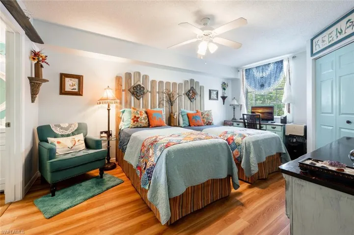 Bedroom with light wood-style flooring, a textured ceiling, a ceiling fan, and a closet