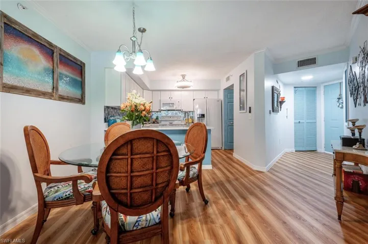 Dining room with light wood-type flooring, baseboards, visible vents, and crown molding