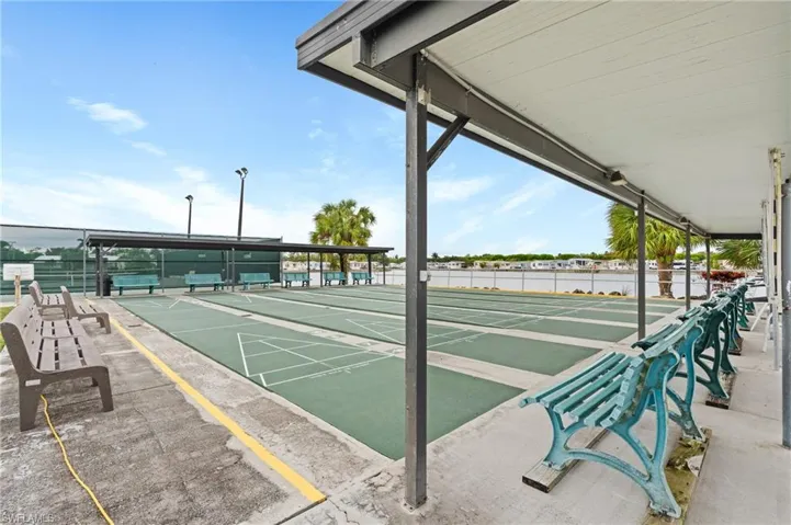 View of home's community with fence and shuffleboard