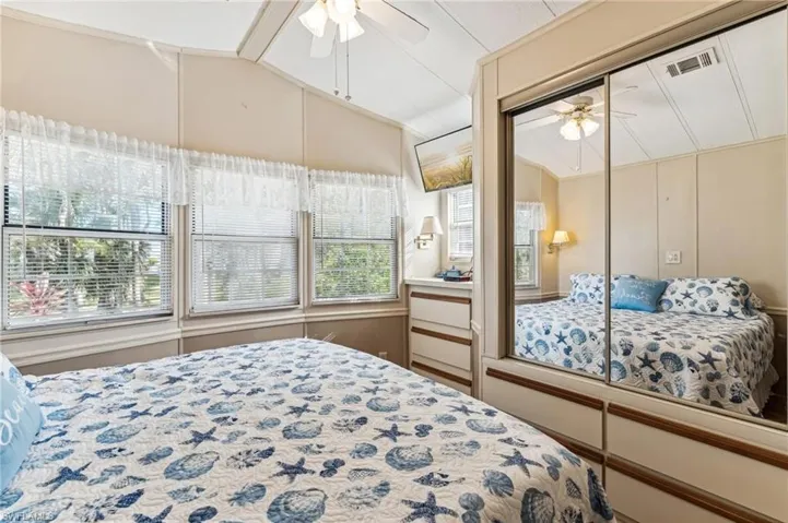 Bedroom with lofted ceiling, visible vents, and ceiling fan