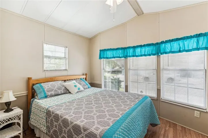 Bedroom with lofted ceiling with beams, baseboards, a ceiling fan, and wood finished floors