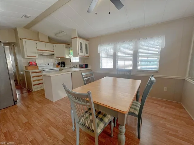 Dining area featuring light floors, lofted ceiling with beams, a ceiling fan, and visible vents