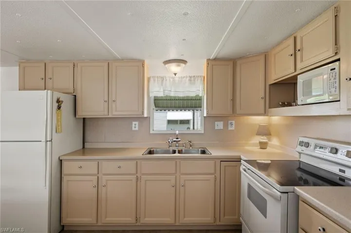 Kitchen featuring sink, a textured ceiling, and white appliances