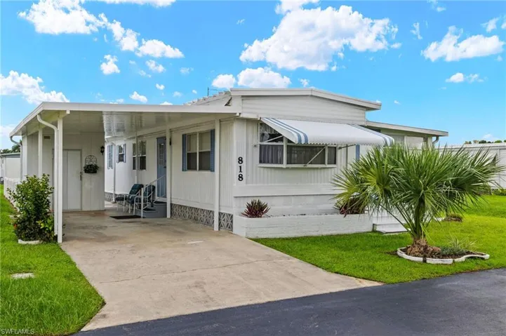 Manufactured / mobile home with a front lawn and a carport
