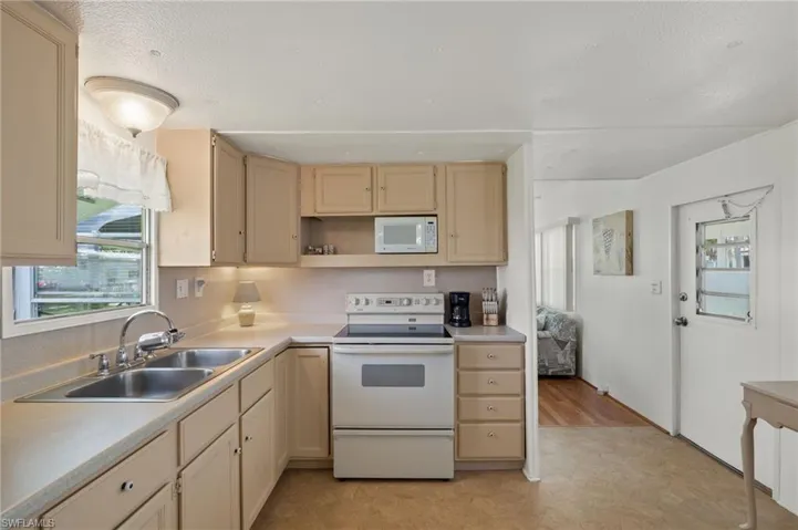 Kitchen with light tile patterned flooring, sink, and white appliances