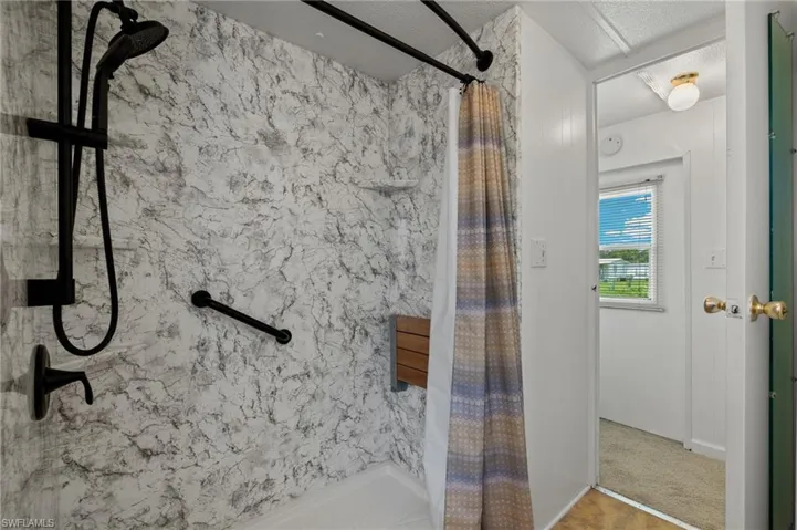 Bathroom with a textured ceiling and curtained shower