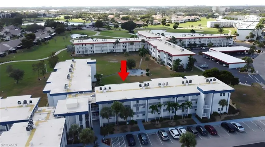 Drone / aerial view of apartment complex / building and a local golf course