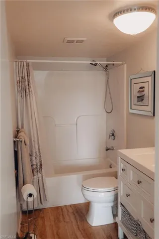 Full bath with shower / tub combo, vanity, and light wood-style floors