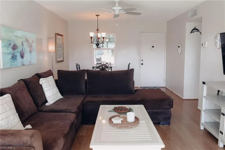 Living area featuring wood finished floors, a chandelier, and a ceiling fan