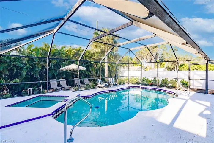 View of pool featuring glass enclosure, a sunroom, a patio area, and a pool with connected hot tub