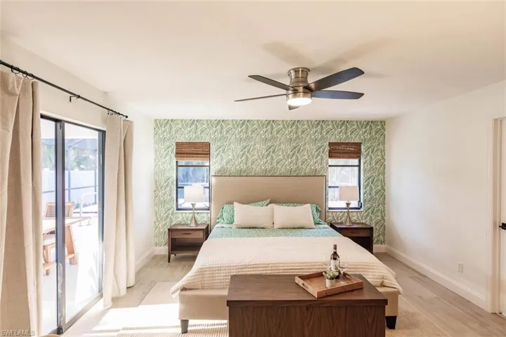 Bedroom featuring wallpapered walls, an accent wall, access to exterior, a ceiling fan, and light wood finished floors