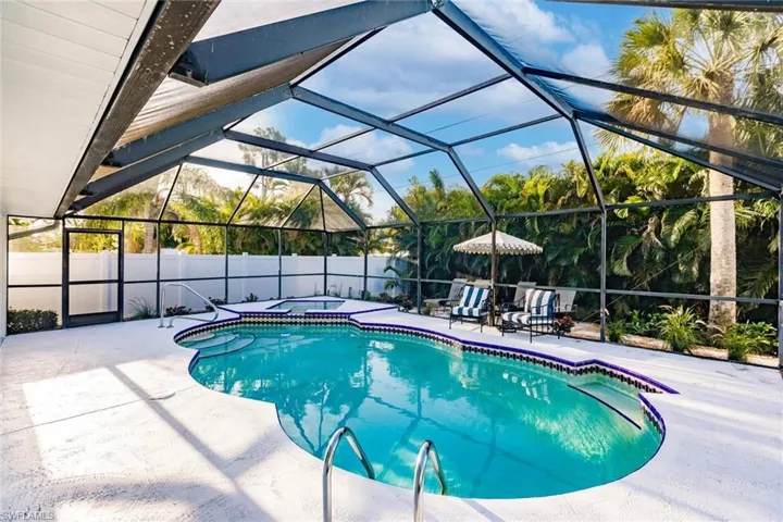 View of swimming pool with glass enclosure, a sunroom, a patio, an in-ground hot tub, and a fenced backyard