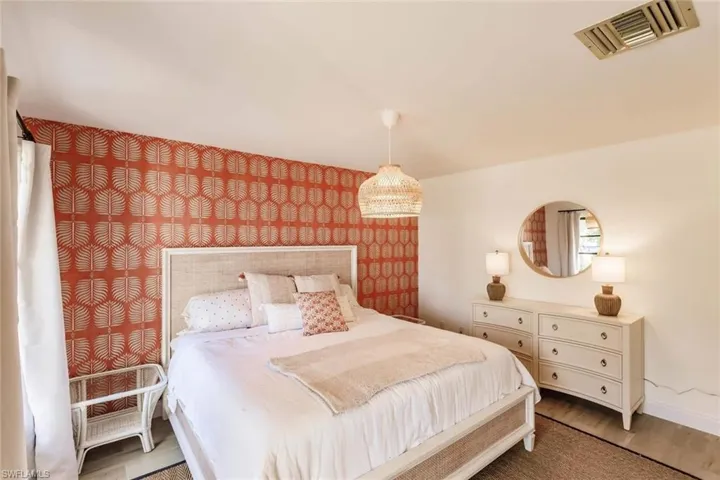 Bedroom featuring an accent wall, wallpapered walls, and wood finished floors