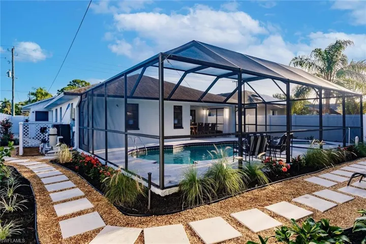 Back of property with a fenced backyard, a sunroom, and glass enclosure