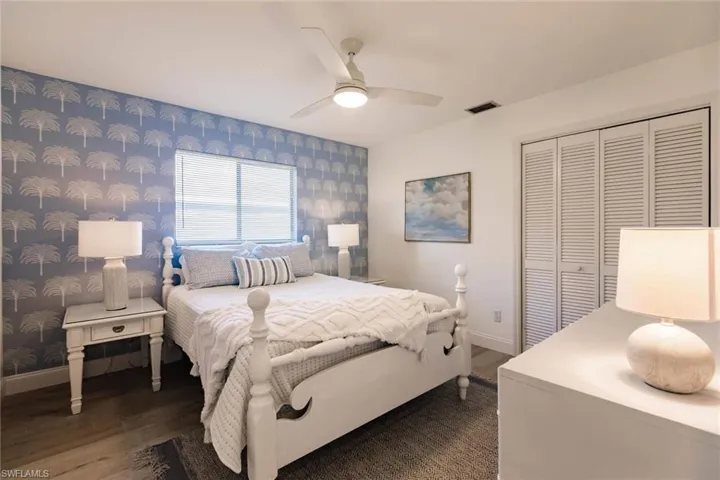 Bedroom with a ceiling fan, a closet, wallpapered walls, and dark wood-style floors