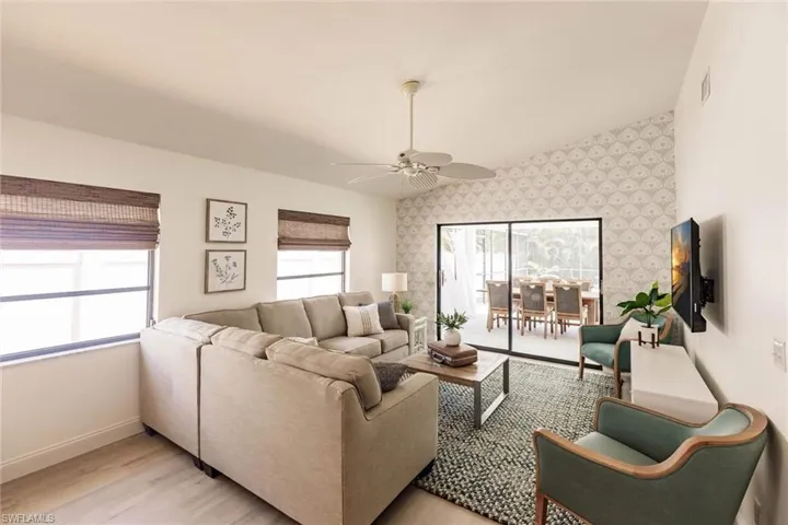 Living room with plenty of natural light, ceiling fan, light wood-type flooring, lofted ceiling, and an accent wall