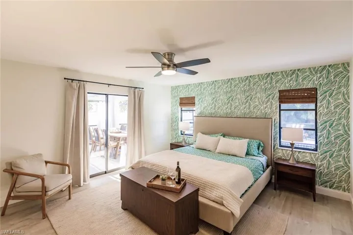Bedroom with wallpapered walls, access to outside, light wood finished floors, a ceiling fan, and an accent wall