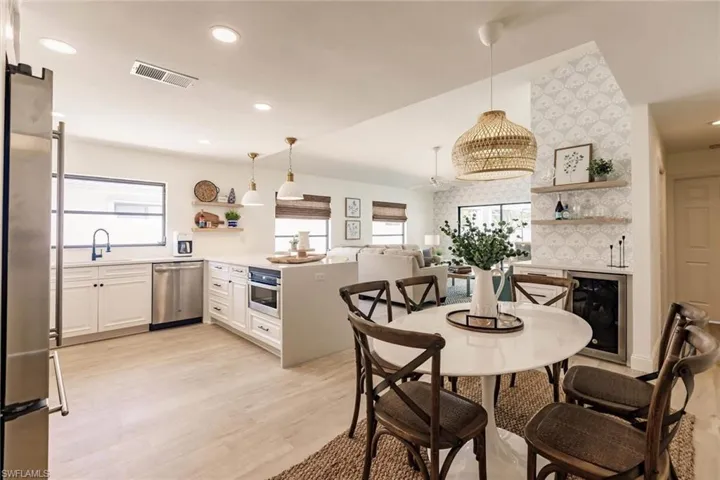 Dining room featuring beverage cooler, light wood-style floors, plenty of natural light, lofted ceiling, and recessed lighting