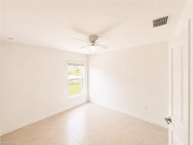 Interior room featuring light-toned tile flooring and white baseboards