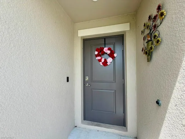Recessed entry featuring a paneled door, stippled stucco exterior, and overhead lighting