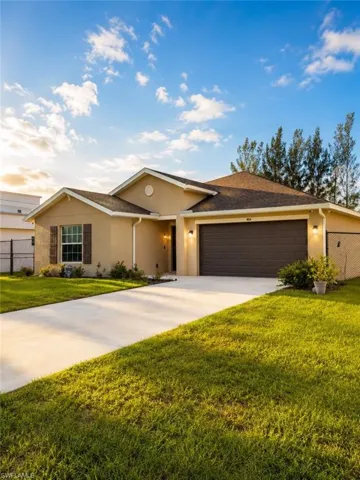 Exterior stucco residence featuring a two-car garage, concrete driveway, and established lawn
