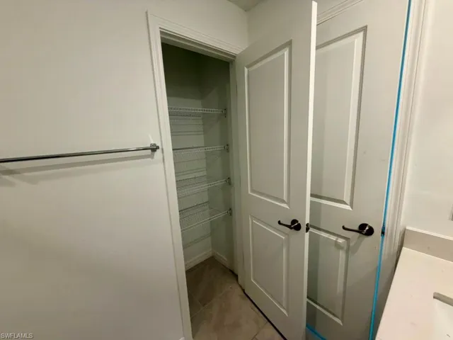 Recessed pantry with wire shelving, light-toned tile flooring, and crisp white trim