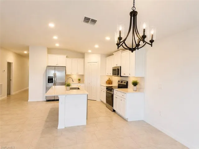 Modern kitchen featuring a central island, white cabinetry, stainless steel appliances, and a tiled backsplash