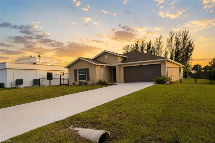 Single-story residence featuring a two-car garage with a paneled door, a paved driveway, and a fenced side yard