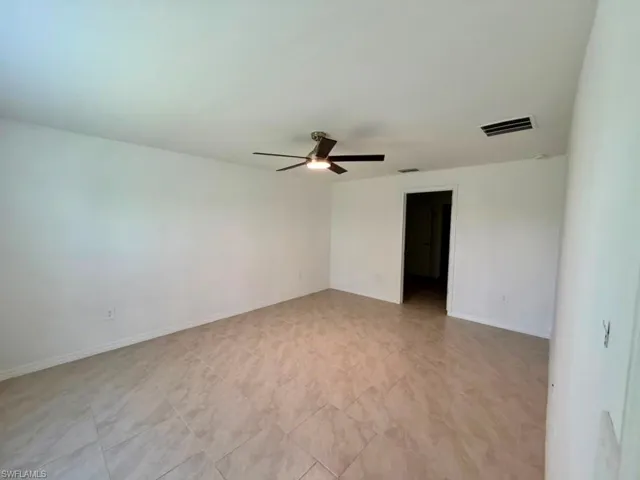 Spacious interior room featuring light-toned tile flooring and crisp white walls