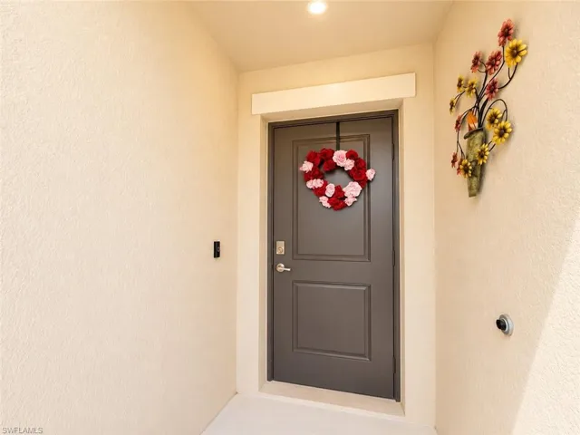 Entryway featuring a dark gray paneled door with brushed nickel hardware, light stucco exterior walls, and a recessed ceiling light