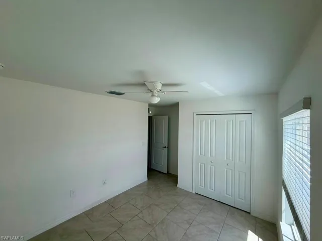 Neutral-toned room featuring a ceiling fan, tiled flooring, and a window with blinds