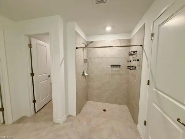 Walk-in shower with light-toned tile surround and flooring