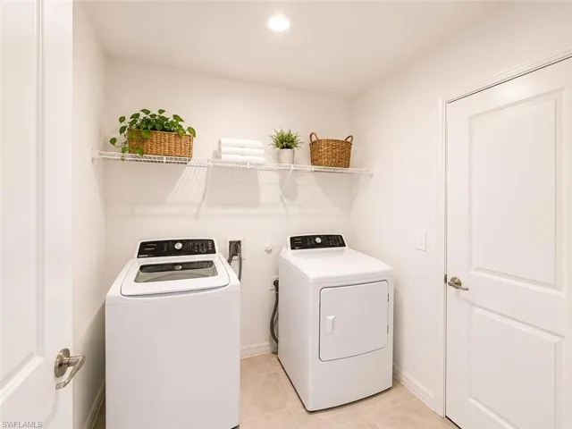 Dedicated laundry area featuring tile flooring, white walls, and a wire shelving unit
