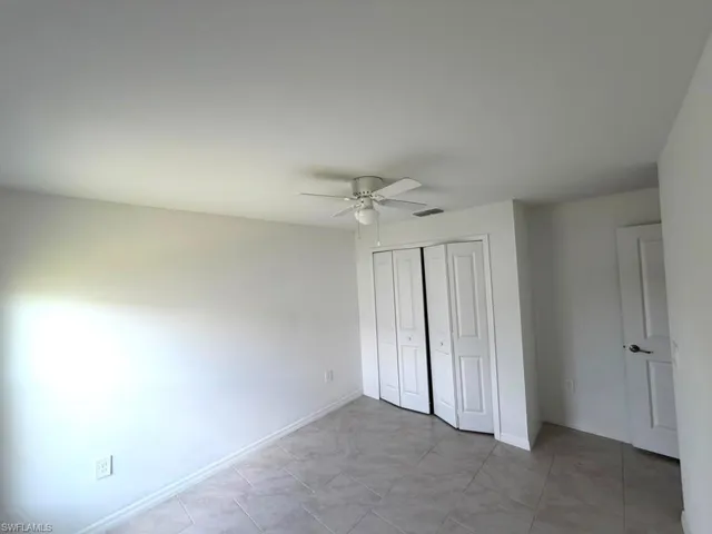 Interior room featuring light-toned tile flooring, white walls, and a ceiling fan