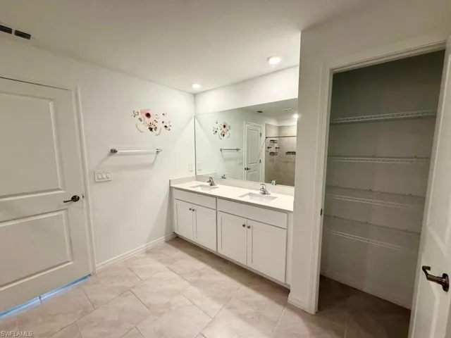 Bathroom featuring a dual-sink vanity with white cabinetry and a full-width mirror