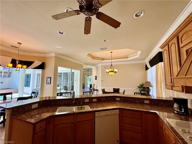 Kitchen featuring suspended lighting, ceiling fan, wood finish cabinetry, white appliances, and ornamental molding