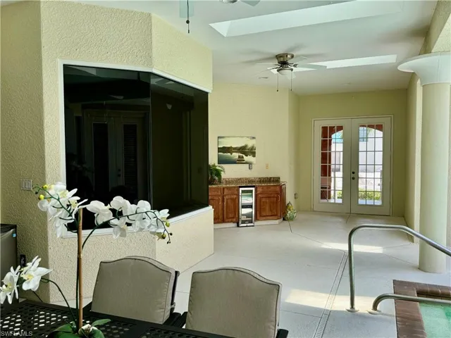Dining area featuring a ceiling fan, french doors, a skylight, wine cooler, and a textured wall